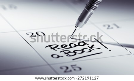 Concept image of a Calendar with a golden dart stick. The words Read a book written on a white notebook to remind you an important appointment.