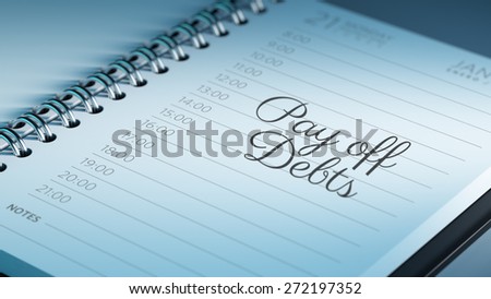 Closeup of a personal calendar setting an important date representing a time schedule. The words Pay off debts written on a white notebook to remind you an important appointment.