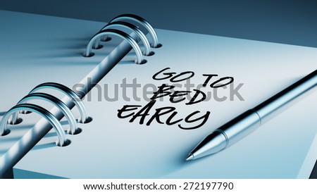 Closeup of a personal agenda setting an important date writing with pen. The words Go to bed early written on a white notebook to remind you an important appointment.