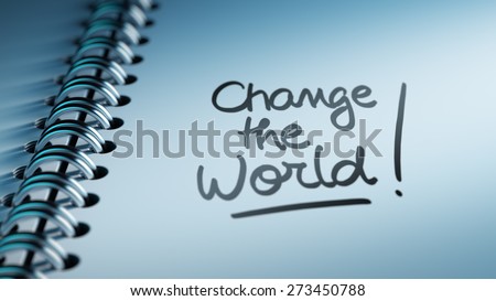 Closeup of a personal calendar setting an important date representing a time schedule. The words Change the world written on a white notebook to remind you an important appointment.