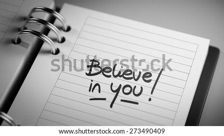 Closeup of a personal agenda setting an important date representing a time schedule. The words Believe in you written on a white notebook to remind you an important appointment.
