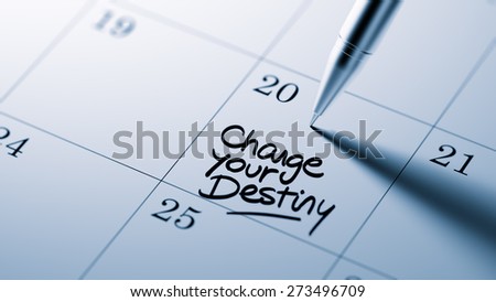 Closeup of a personal agenda setting an important date written with pen. The words Change your destiny written on a white notebook to remind you an important appointment.
