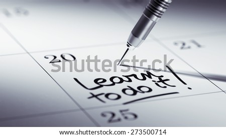 Concept image of a Calendar with a golden dart stick. The words Learn to do it written on a white notebook to remind you an important appointment.