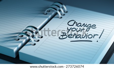 Closeup of a personal agenda setting an important date representing a time schedule. The words Change your behavior written on a white notebook to remind you an important appointment.