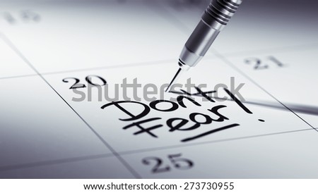 Concept image of a Calendar with a golden dart stick. The words Don\'t Fear written on a white notebook to remind you an important appointment.