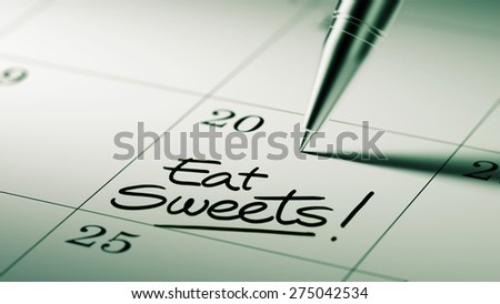 Closeup of a personal agenda setting an important date written with pen. The words Eat Sweets written on a white notebook to remind you an important appointment.