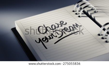 Closeup of a personal agenda setting an important date representing a time schedule. The words Chase your dream written on a white notebook to remind you an important appointment.