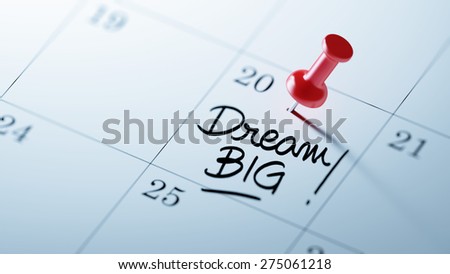 Concept image of a Calendar with a red push pin. Closeup shot of a thumbtack attached. The words Dream big written on a white notebook to remind you an important appointment.
