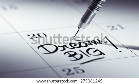 Concept image of a Calendar with a golden dart stick. The words Dream big written on a white notebook to remind you an important appointment.