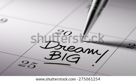 Closeup of a personal agenda setting an important date written with pen. The words Dream big written on a white notebook to remind you an important appointment.