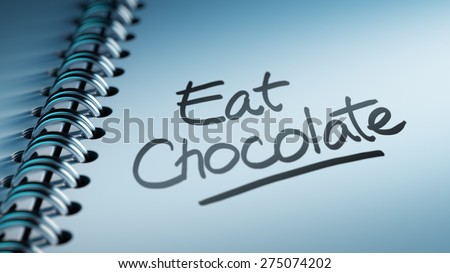 Closeup of a personal calendar setting an important date representing a time schedule. The words Eat Chocolate written on a white notebook to remind you an important appointment.