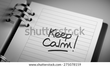 Closeup of a personal agenda setting an important date representing a time schedule. The words Keep Calm written on a white notebook to remind you an important appointment.
