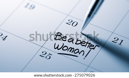 Closeup of a personal agenda setting an important date written with pen. The words Be a better woman written on a white notebook to remind you an important appointment.