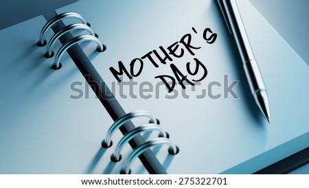 Closeup of a personal agenda setting an important date writing with pen. The words Mother\'s Day written on a white notebook to remind you an important appointment.