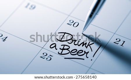 Closeup of a personal agenda setting an important date written with pen. The words Drink a beer written on a white notebook to remind you an important appointment.