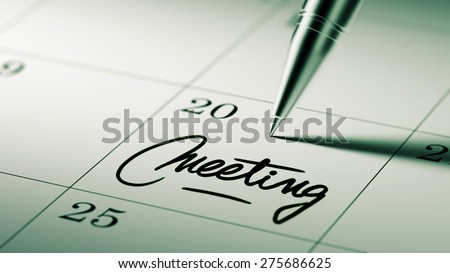 Closeup of a personal agenda setting an important date written with pen. The words Meeting written on a white notebook to remind you an important appointment.