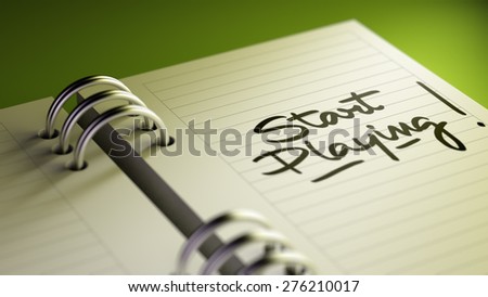Closeup of a personal agenda setting an important date representing a time schedule. The words Start Playing written on a white notebook to remind you an important appointment.