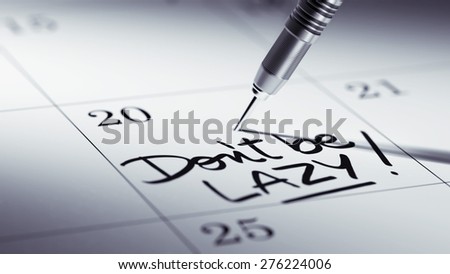 Concept image of a Calendar with a golden dart stick. The words Don\'t be Lazy written on a white notebook to remind you an important appointment.