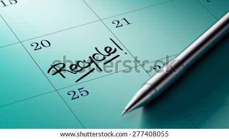 Closeup of a personal agenda setting an important date written with pen. The words Recycle written on a white notebook to remind you an important appointment.