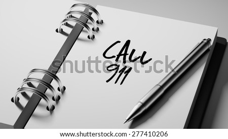 Closeup of a personal agenda setting an important date writing with pen. The words Call 911 written on a white notebook to remind you an important appointment.