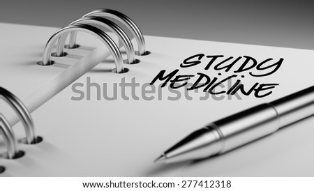 Closeup of a personal agenda setting an important date writing with pen. The words Study Medicine written on a white notebook to remind you an important appointment.