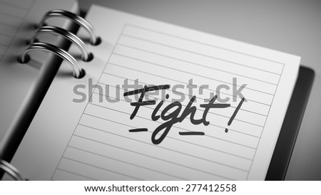 Closeup of a personal agenda setting an important date representing a time schedule. The words Fight written on a white notebook to remind you an important appointment.
