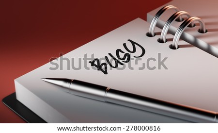 Closeup of a personal agenda setting an important date writing with pen. The words Busy written on a white notebook to remind you an important appointment.