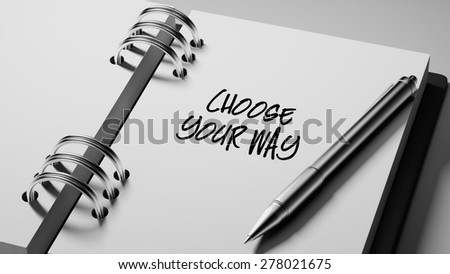 Closeup of a personal agenda setting an important date writing with pen. The words Choose your way written on a white notebook to remind you an important appointment.