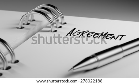 Closeup of a personal agenda setting an important date writing with pen. The words Agreement written on a white notebook to remind you an important appointment.