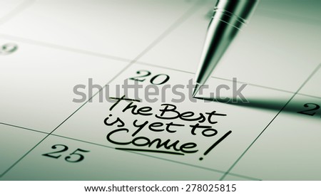Closeup of a personal agenda setting an important date written with pen. The words The best is yet to come written on a white notebook to remind you an important appointment.