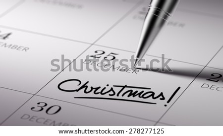 Closeup of a personal agenda setting an important date written with pen. The words Christmas written on a white notebook to remind you an important appointment.