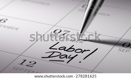 Closeup of a personal agenda setting an important date written with pen. The words Labor Day written on a white notebook to remind you an important appointment.