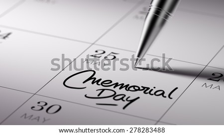 Closeup of a personal agenda setting an important date written with pen. The words Memorial Day written on a white notebook to remind you an important appointment.