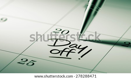 Closeup of a personal agenda setting an important date written with pen. The words Day off written on a white notebook to remind you an important appointment.