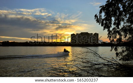 Young guy cruising in the lake on a jet ski during sunset.