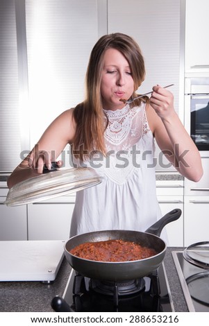 attractive student cooking bolognese sauce in kitchen