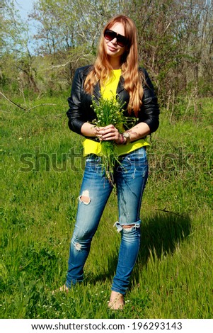 The photo shows a girl in a yellow blouse and blue jeans. Picture taken in the countryside.