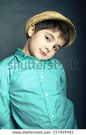 young cute boy with a tilted head, wearing hat, vertical studio shot