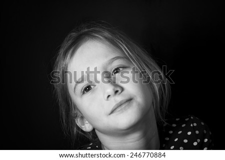 Portrait of a beautiful teenage girl with a distant gaze and tilted head, studio shot in black and white