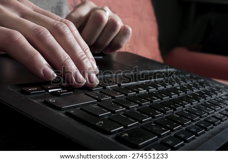 Closeup shot of female hands typing on a black laptop, indoor shot with blurred background