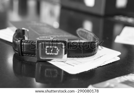 Wrist watch in focus, passport and boarding pass blurred, concept of travel in black and white