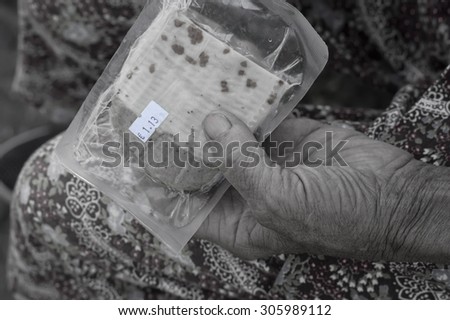 Abstract food with sticker price tag in european currency in aged female hands, digitally altered cropped shot