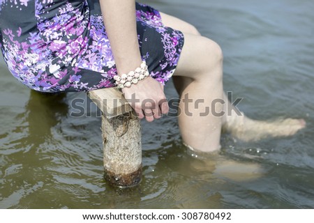 Woman sitting on a bench and cooling her bare feet in water, outdoor cropped shot