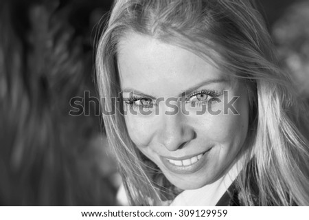 Portrait of a happy beautiful young woman, outdoor shot with blurred background in black and white