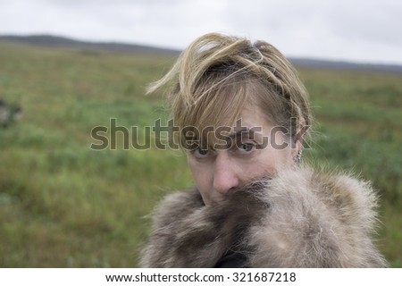 Portrait of a middle aged woman wrapping up in fur jacket, posing outdoors