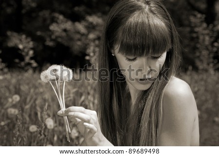 fragile girl holding dandelions in hand. blowball