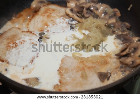 meat with sauce and mushrooms cooked on a frying pan