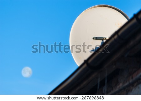 satellite dish on the roof on the background of the moon in the sky