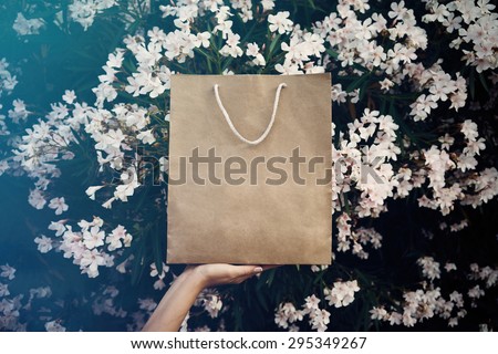 girl holding a bag with one hand on the background flowers