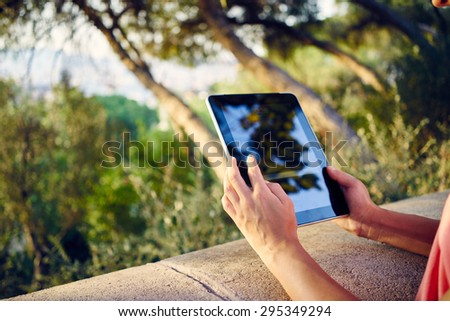 Woman using digital tablet PC in the park. Girl holding the tablet on a background of trees